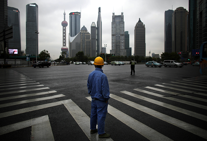 A construction worker looks at Pudong financial district as he wait to cross an avenue in Shanghai May 30, 2013. (Reuters / Carlos Barria)