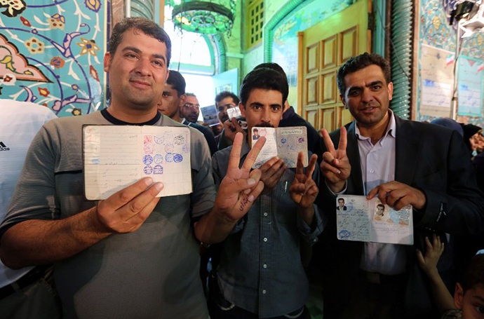 Iranian men show their documents as they vote in the first round of the presidential election at a polling station in Tehran on June 14, 2013. (AFP Photo / Atta Kenare)