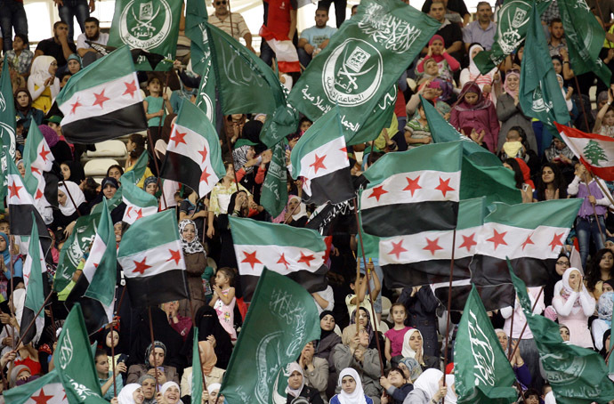 Syrians and Lebanese wave Syria's former independence flag which has been adopted by the rebels forces fighting agianst Syrian pro-government forces in Syria, and the green Sunni Muslim Jamaa Islamiya flag as they gather in the main sports stadium in the southern Lebanese city of Sidon on June 9, 2013 in solidarity with the Syrian central city of Qusayr which fell to government forces, aided by Lebanon's Hezbollah fighters, earlier in the week. (AFP Photo)