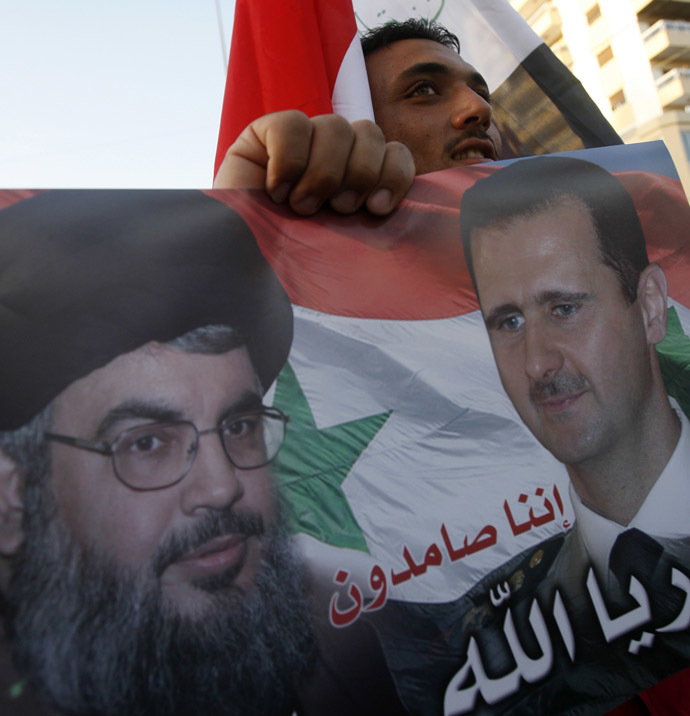 A man carries a placard bearing the portraits of Syrian President Bashar al-Assad and Hezbollah leader Hassan Nasrallah, during a gathering to celebrate the capture of the city of Qusayr by Syrian pro-government forces, in the southern Lebanese city of Sidon, on June 6, 2013. (AFP Photo)