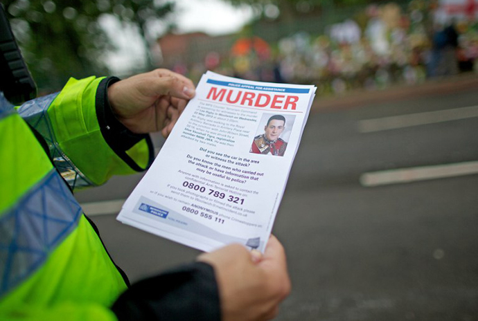 A police officer holds a leaflet requesting information about the murder of Drummer Lee Rigby of the 2nd Battalion the Royal Regiment of Fusiliers outside Woolwich Barracks in London, on May 29, 2013. (AFP Photo / Andrew Cowie)