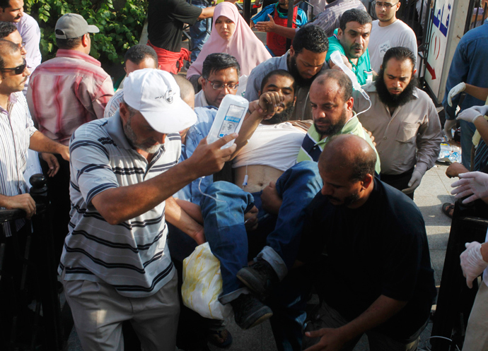 Supporters of deposed Egyptian president Mohamed Mursi help a wounded supporter outside the Republican Guard headquarters in Cairo, July 8, 2013 (Reuters / Asmaa Waguih)