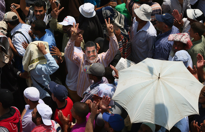 Egyptian supporters of the Muslim Brotherhood and deposed president Mohamed Morsi, sporting a cartoon mask of the toppled leader, flashes the sign of victory during a rally outside Cairo's Rabaa al-Adawiya mosque on July 12, 2013, following Friday noon prayer (AFP Photo / Marwan Naamani) 