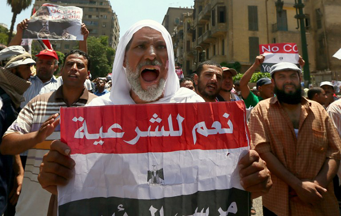 A supporter of the Muslim Brotherhood and Egypt's ousted president Mohamed Morsi, holds up a paper Egyptian flag with the words in Arabic, "Yes to Legitimacy" as they demonstrate along a road leading to the government headquarter on July 17, 2013. (AFP Photo / Marwan Naamani)