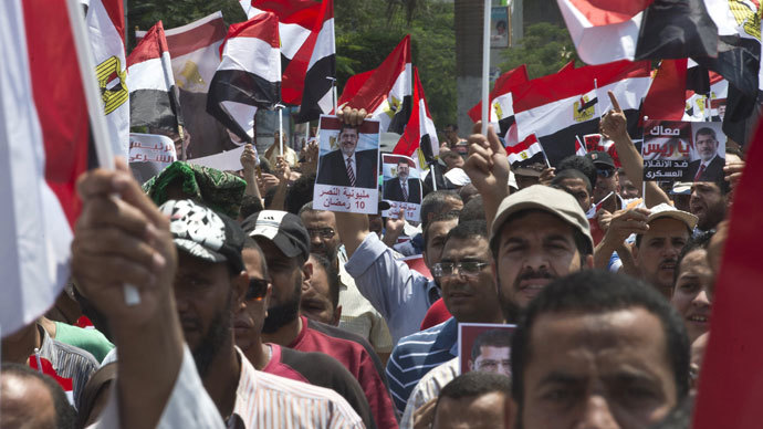 Supporters of the Muslim Brotherhood and ousted Egyptian president Mohamed Morsi wave Egyptian flags while holding pictures of Morsi as they march towards Cairo University to demand his reinstatement in Cairo on July 19, 2013.(AFP Photo / Khaled Desouki)