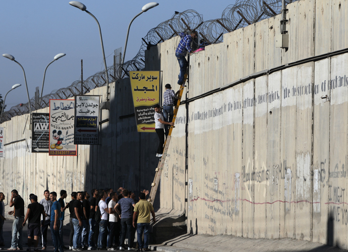 Palestinian men climb a section of Israel's separation barrier as they try to avoid crossing Israeli-controlled checkpoints to reach the al-Aqsa mosque compound in Jerusalem's Old City, on July 26, 2013, on the third Friday of the holy month of Ramadan (AFP Photo / Abbas Momani) 