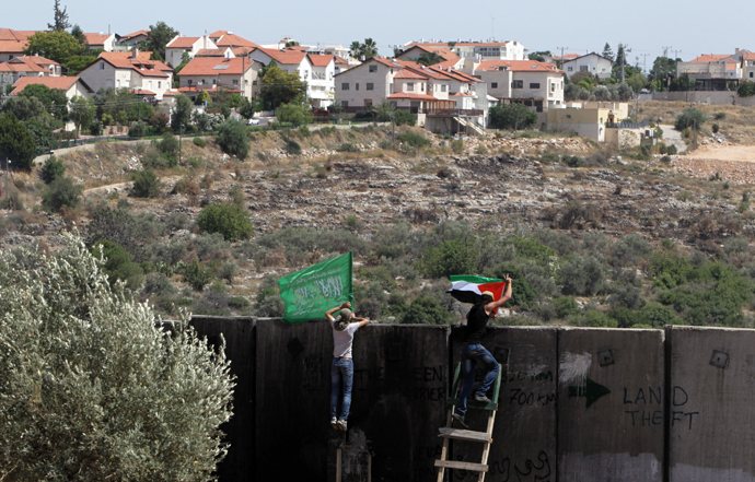 Palestinian protester climbs Israel's controversial separation barrier during clashes with Israeli security forces following a demonstration against Israeli settlements and its separation wall, in the West Bank village of Nilin near the Jewish settlement of Hashmonaim (background), on June, 7, 2013 (AFP Photo / Abbas Momani) 