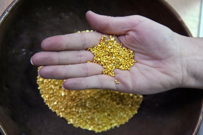 A worker holds up a palm full of gold granules (Reuters / Srdjan Zivulovic)