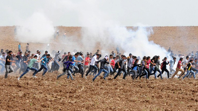Protestors flee as tear gas explodes in a field during a demonstration near Dicle University, in Diyarbakir, on April 9, 2013. Leftist Kurdish students protest after clashes between left and right-wing groups inside Dicle University. (AFP Photo / Mehmet Engin)