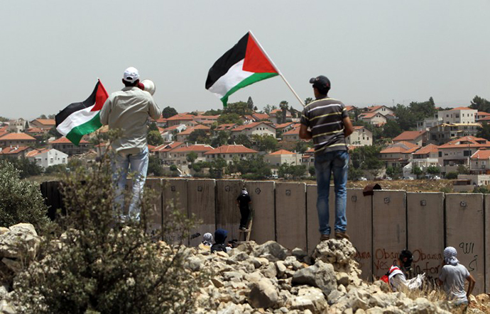 Palestinian protesters wave the national flag as their comrades climb Israel's controversial separation barrier. (AFP Photo / Abbas Momani)