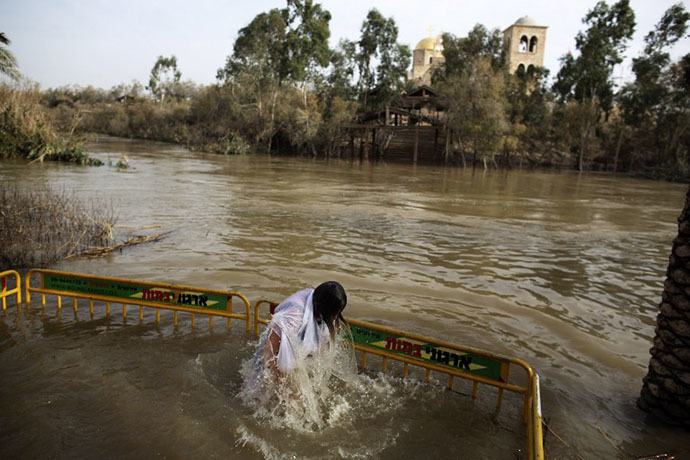 Christian Orthodox pilgrim immerses herself into the waters of the Jordan River during a baptism ceremony marking the Orthodox Feast of the Epiphany on January 18, 2013 at the Qasr al-Yahud baptismal site in the West Bank by the Jordan River. (AFP Photo / Menahem Kahana)