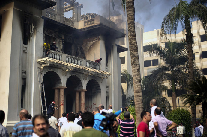 Bystanders, firefighters and workers stand by the Giza Governorate headquarters after it was -according to Egyptian State TV- torched by Islamists on August 15, 2013 in Cairo, Egypt (AFP Photo / Gianluigi Guercia) 