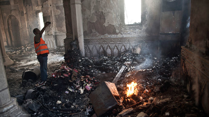 An Egyptian man stands near a burning fire as he takes a picture of the damage at Rabaa al-Adawiya mosque in Cairo on August 15, 2013, following a crackdown on the protest camps of supporters of Egypt's ousted Islamist leader Mohamed Morsi the previous day. (AFP Photo / Mahmoud Khaled)