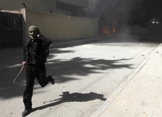 A fighter from Islamist Syrian rebel group Jabhat al-Nusra runs with his weapon as their base is shelled in Raqqa province, eastern Syria, March 14, 2013. (Reuters/Hamid Khatib)