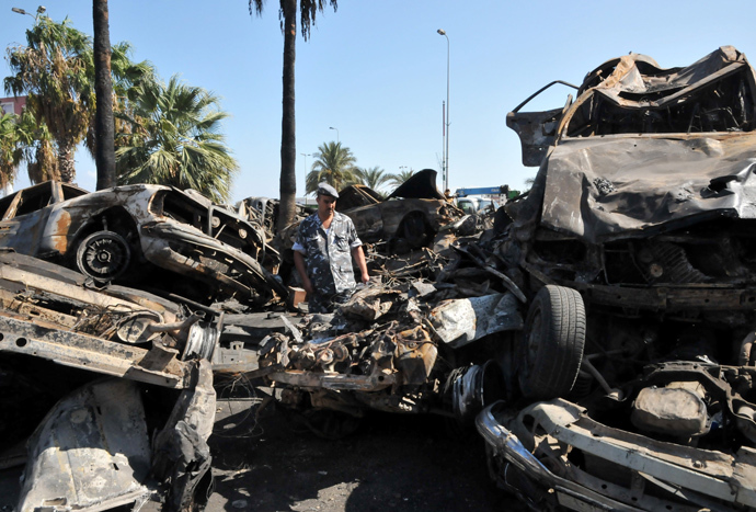 A Lebanese soldier inspect burnt vehicles on August 24, 2013 on the site of a bombing outside Al-Taqwa mosque the day before in the northern city of Tripoli (AFP Photo / Ibrahim Chalhoub)