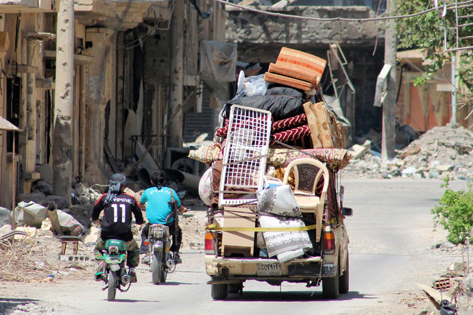 yrian young men drive their motorbikes past a pick up truck loaded notably with matresses, chairs and carpets in a street of the old airport neighbourhood of the Syria's eastern town of Deir Ezzor on August 27, 2013. (AFP Photo)