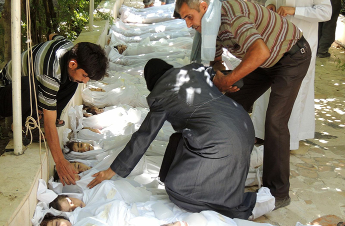 A woman mourning over a body wrapped in shrouds laid out in a line on the ground with other victims which Syrian rebels claim were killed in a toxic gas attack by pro-government forces in eastern Ghouta, on the outskirts of Damascus on August 21, 2013. (AFP Photo / Daya Al-Deen)