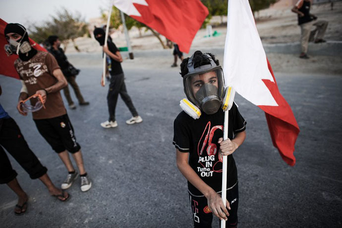 A young Bahraini protestor holds the national flag during the clashes with riot police following an anti-regime protest in the village of Abu Saiba, west of Manama, on August 15, 2013. (AFP Photo / Mohammed Al-Shaikh)