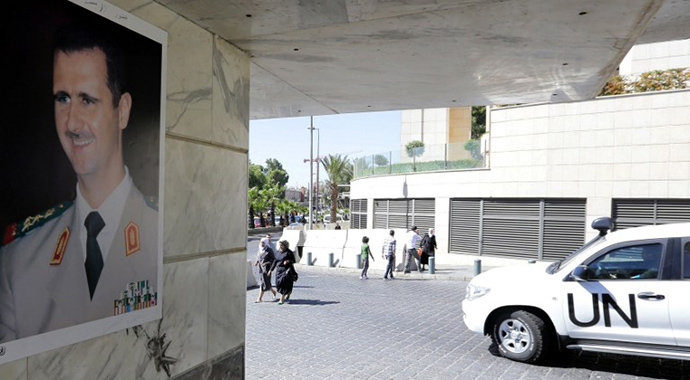 (FILES) A photo taken on October 9, 2013 shows a poster of Syrian President Bashar al-Assad on a wall as a United Nations vehicle carrying inspectors from the Organisation for the Prohibition of Chemical Weapons (OPCW) leaving a hotel in Damascus (AFP Photo / Louai Beshara)