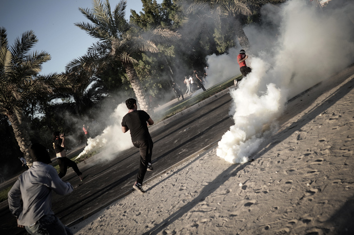 Bahraini protesters run away from tear gas and bird shot fired by riot police during clashes following the funeral of Ali Khalil Sabbagh in the village of Bani Jamrah, west of Manama, on October 23, 2013 (AFP Photo / Mohammed Al-Shaikh) 