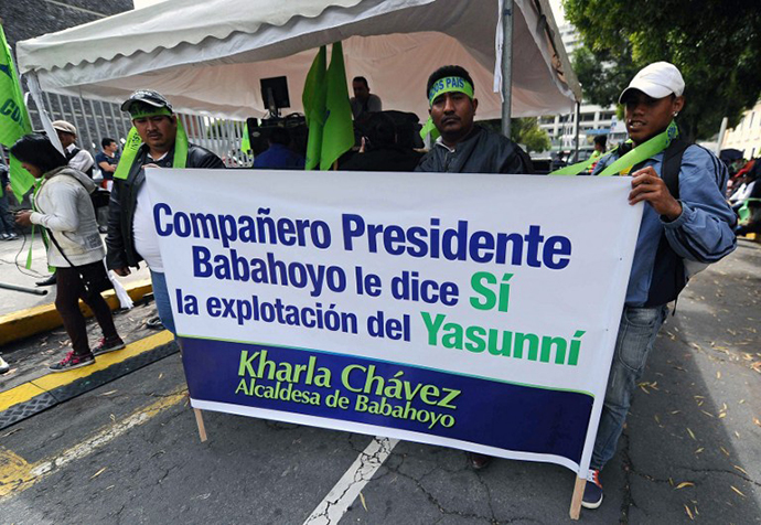 Supporters of President Rafael Correa, backing oil drilling in the Yasuni National Park, hold banners outside the National Assembly building in Quito on October 3, 2013, as lawmakers decide their vote on Correa's request for the exploitation. (AFP Photo / Rodrigo Buendia)