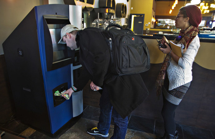 A customer puts money into the world's first ever permanent bitcoin ATM unveiled at a coffee shop in Vancouver, British Columbia October 29, 2013. (Reuters/Andy Clark)