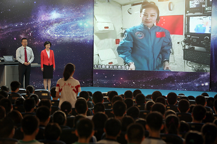 A girl in a school in Beijing asks Chinese female astrounaut Wang Yaping (Top R) questions as Wang delivers a lesson to students from Tiangong-1 space module in the morning of June 20, 2013. (AFP Photo)