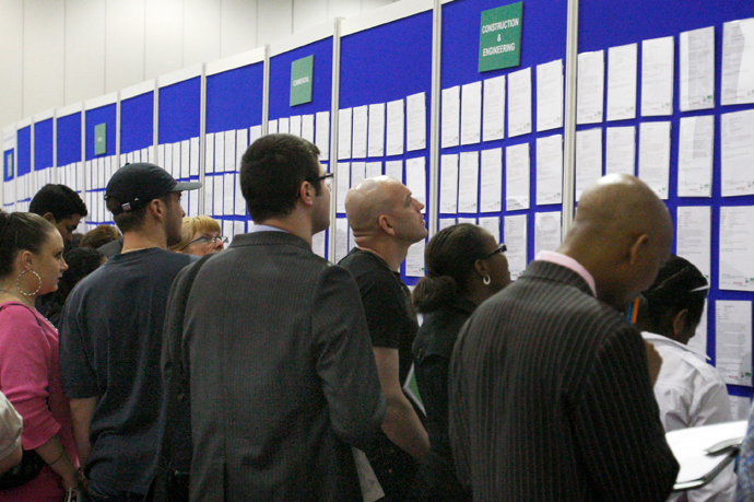 People look at job listings at the Careers and Jobs Live careers fair at the ExCeL centre in London (Reuters / Luke MacGregor)