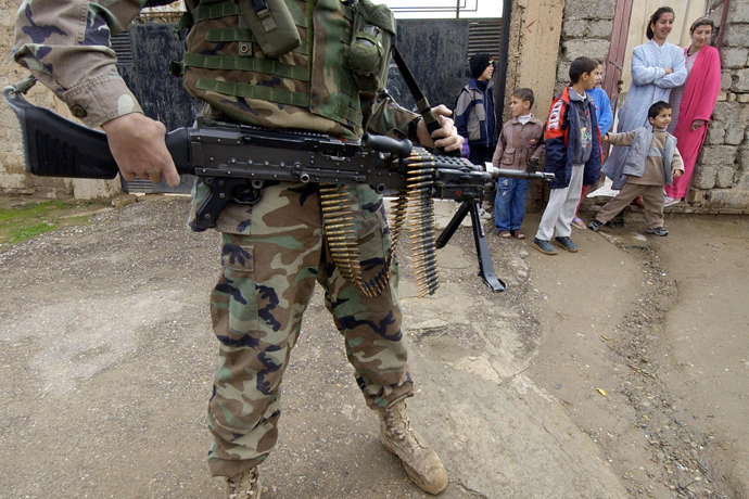 Iraqi children look at US soldiers from the 1st battalion, 22nd Regiment of the 4th Infantry Division conducting a foot-patrol along a street of former Iraqi dictator Saddam Hussein's hometown Tikrit, 180 Kilometers (110 miles) north of Iraqi capital Baghdad, 27 December 2003 (AFP Photo / Jewel Samad) 