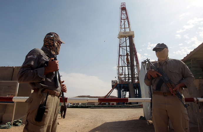 Gazprom security men stand guard in front of a drilling platform at an oilfield near the Iraqi city of Badra, south of Baghdad, on October 18, 2012. (AFP Photo)