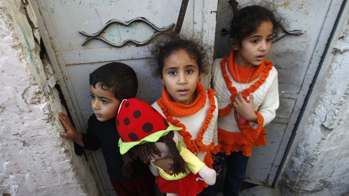 Palestinian children stand at the gate of their home as they watch the funeral procession of killed members of the Hejazi family, including two young children, in Beit Lahia, in the northern Gaza Strip.(AFP Photo / Mohammed Abed)