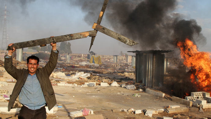 A man holds up a broken wooden structure in a burnt makeshift Syrian refugee camp after it was attacked by residents of the neighbouring eastern Lebanese village of Qsar Naba near Zahle in the Bekaa valley, on December 2, 2013. (AFP Photo / STR)