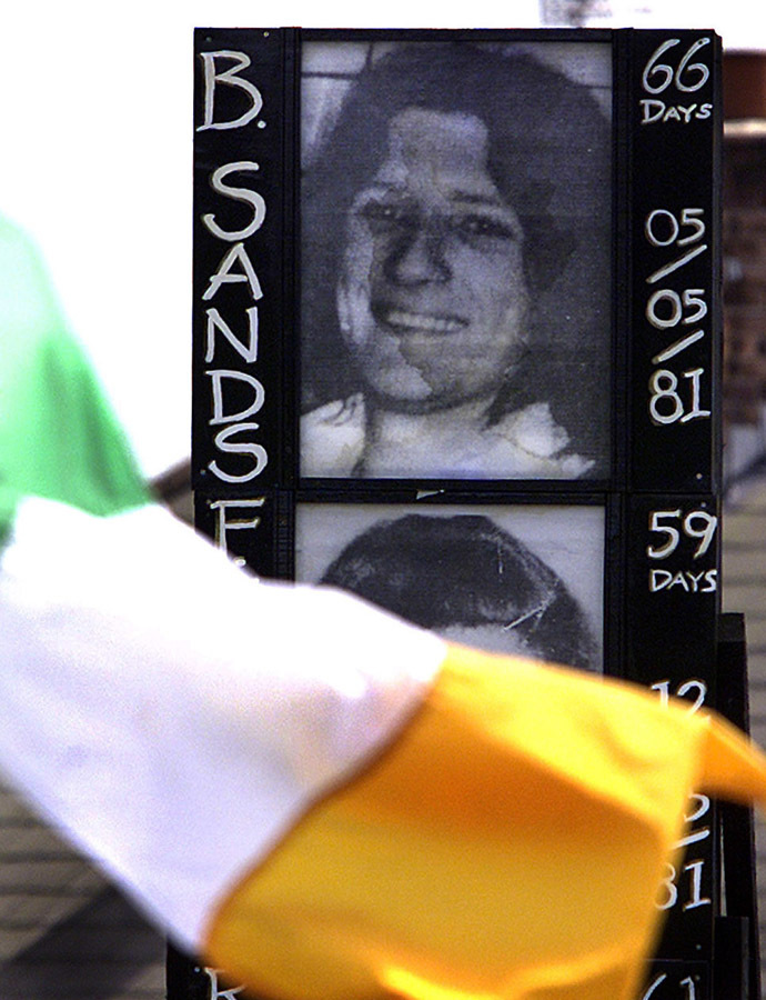 An Irish flag flutters in the wind May 3, 2001 in front of a picture of republican hunger striker, Bobby Sands, who died after 66 days on the hunger strike in the Maze twenty years ago tomorrow.(Reuters)