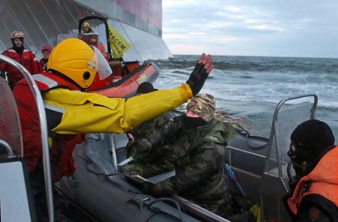 A handout photo taken by Greenpeace on September 18, 2013, shows a camouflage clad mask wearing officer of Russian Coast Guard (C) pointing a knife at a Greenpeace International activist (L) during an environmentalists' attempt to climb Gazpromâs âPrirazlomnayaâ Arctic oil platform somewhere off Russia north-eastern coast in the Pechora Sea. (AFP Photo / Greenpeace / DenisSINYAKOV)