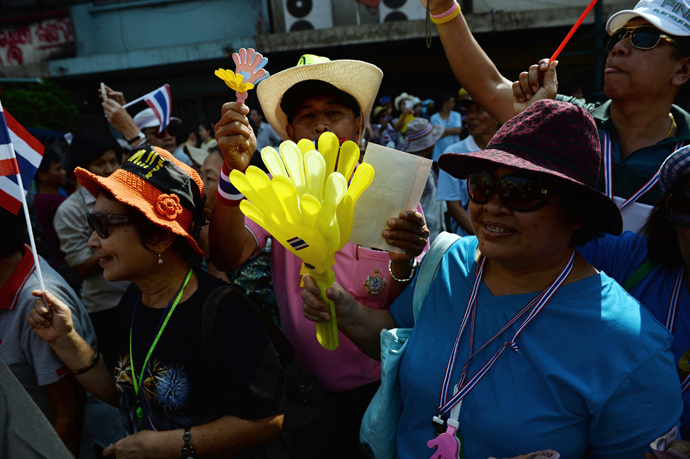 Thai anti-government protesters wave clappers and national flags as they line up the streets during a march led by protest leader Suthep Thaugsuban (unseen) in Bangkok on January 9, 2014 (AFP Photo / Christophe Archambault)