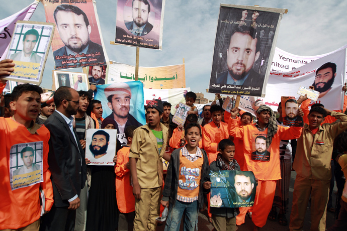  Relatives of Yemeni prisoners being held at the US-run Guantanamo Bay detention camp march in orange jumpsuits while holding their pictures during a demonstration calling for their release outside the US embassy in the capital Sanaa, on January 11, 2014. (AFP Photo / Mohammed Huwais)