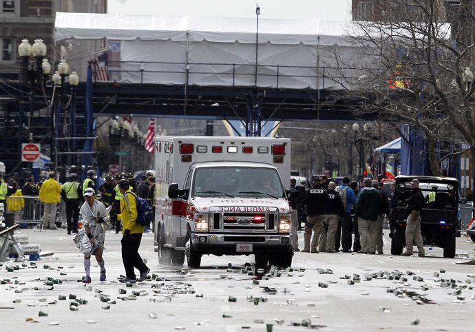 A runner is escorted from the scene after explosions went off at the 117th Boston Marathon in Boston, Massachusetts April 15, 2013. (Reuters/Jessica Rinaldi)