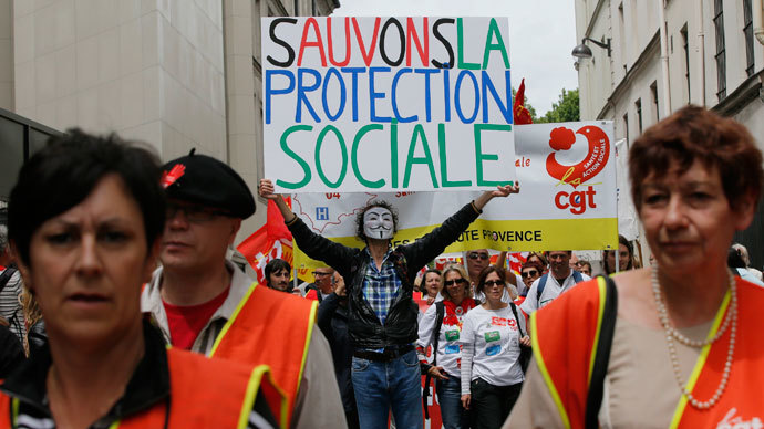 A protester wearing a Guy Fawkes mask holds up a placard during a demonstration by health care professionals against the government's austerity reforms in Paris June 15, 2013.(Reuters / Gonzalo Fuentes)