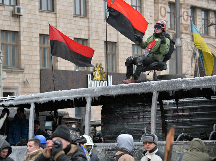 A protester sits on a chair on a burned bus during clashing break of the opposition and the police in Kiev on January 21, 2014. (AFP Photo / Sergei Supinsky)