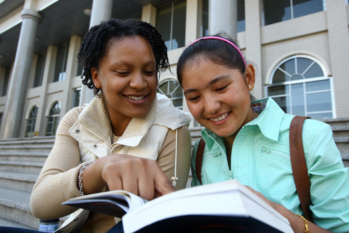 US Afro American student Merisha Enoe (L) and her Chinese mate read a book in Xinjiang Agricultural University in Urumqi, Xinjiang (AFP Photo)