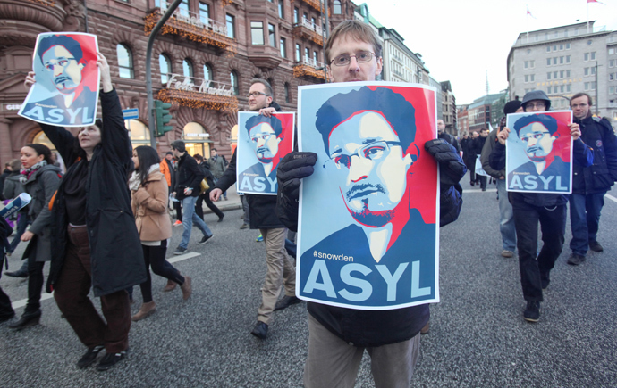 Protestors hold up placards featuring a picture of former NSA contractor Edward Snowden and with the world Asylum on it during a march against the spying methods of the US in Hamburg, northern Germany on December 28, 2013. (AFP Photo / DPA / Bodo Marks)