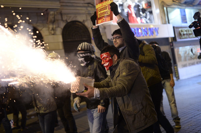 A protestor wearing a red Anonymous mask directs fireworks toward anti-riot police during a protest against Turkish government's newly proposed restrictions on the use of internet, on Istiklal avenue in Istanbul, on February 8, 2014. (AFP Photo / Bulent Kilic)