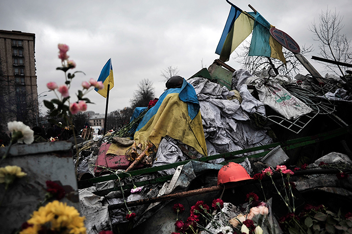 Flags, flowers and a helmet are left on a barricade in central Kiev in homage to demonstrators killed during last week's clashes in central Kiev on February 25, 2014 (AFP Photo / Louisa Gouliamaki)