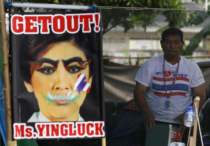 An anti-government protester stands next to a defaced image of Thailand's Prime Minister Yingluck Shinawatra during a rally near the Government Complex in Bangkok February 18, 2014. (Reuters)