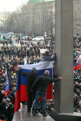 Pro-Russian protesters raise a Russian flag in front of the regional administration building during a rally in the industrial Ukrainian city of Donetsk on March 1, 2014 (AFP Photo / Alexander Khudoteply)