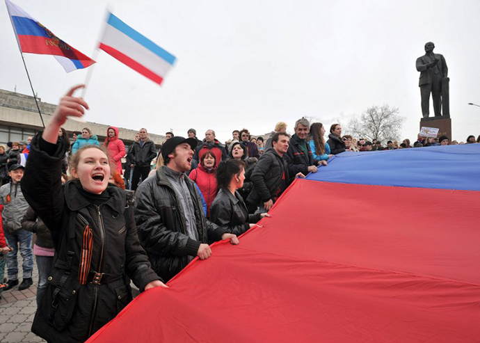 Pro-Russian activists hold a giant Russian flag near a statue of Lenin as they rally in Simferopol, the administrative center of Crimea, on March 1, 2014. (AFP Photo / Genya Savilov)
