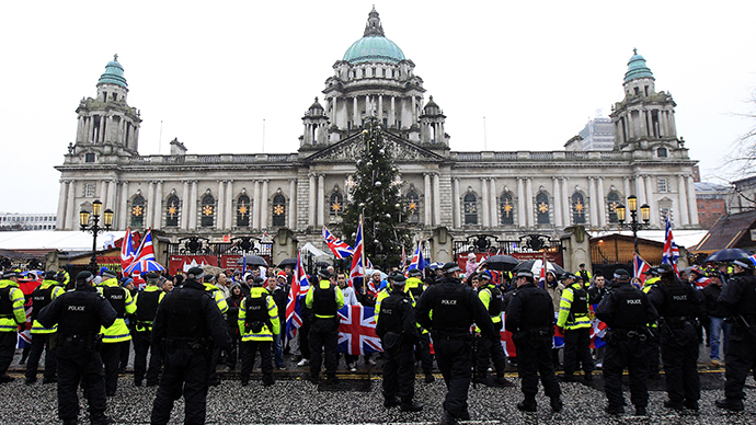 Police in riot gear look on as protesters wave Union Flags in front of the City Hall provoked by a decision to remove the British flag from Belfast's City Hall (Reuters / Cathal McNaughton)