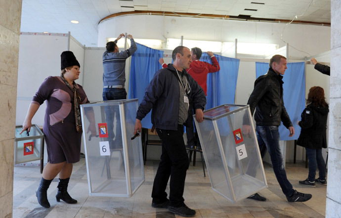 Employees carry ballot boxes as the others prepare the polling booth in one of the polling stations of Sevastopol on March 15, 2014, on the eve of the referendum in Crimea. (AFP Photo / Viktor Drachev) 
