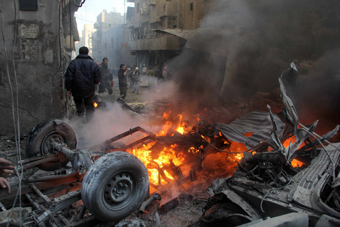 People gather around a burning vehicle following reported shelling by government forces on Bustan al-Qasr neighbourhood on February 26, 2014 in the northern Syrian city of Aleppo. (AFP Photo / Aleppo Media Centre / Mohammed Wesam) 