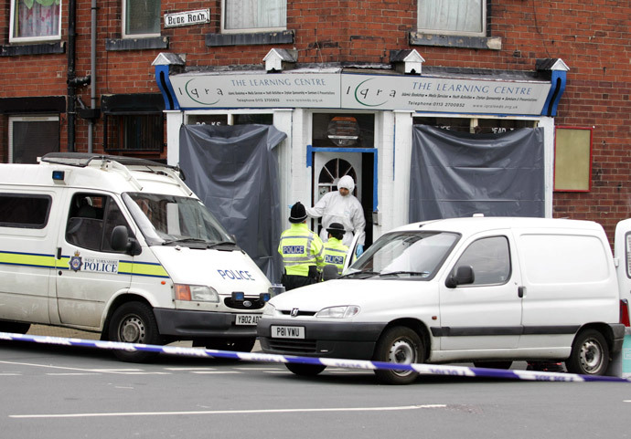 Policemen talk to a forensic expert on the steps of an Islamic bookshop that was raided as part of a fast moving investigation into the London bombings on Bude Road in Leeds, 18 July 2005. (AFP Photo / Steve Parkin) 